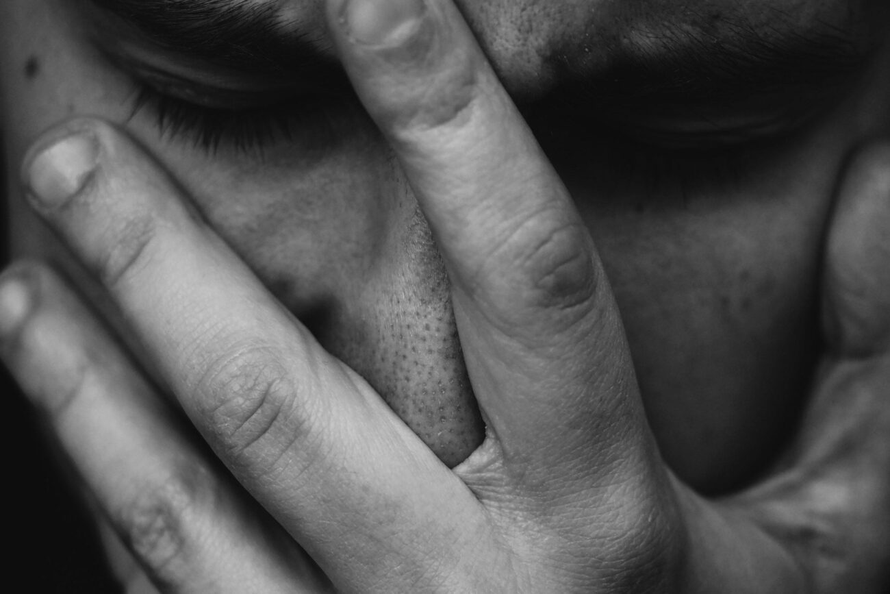 grayscale photo of person placing hand on face