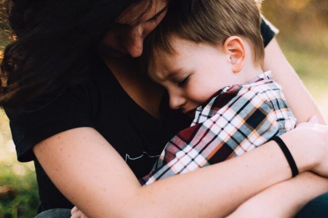 woman hugging boy on her lap
