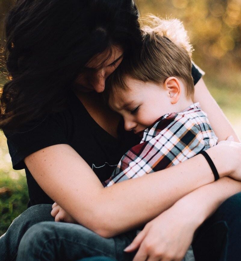 woman hugging boy on her lap