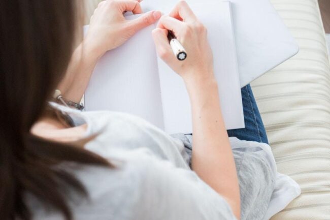 woman writing on white paper