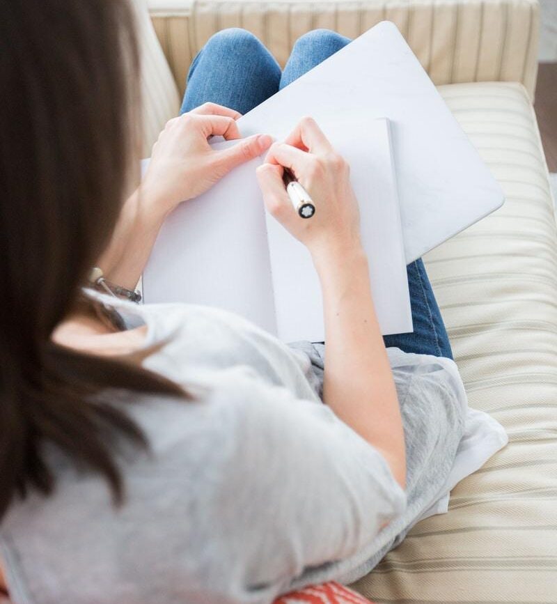 woman writing on white paper
